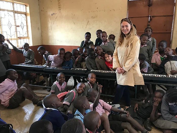 Katya standing in a classroom full of schoolchildren gathered around a keyboard